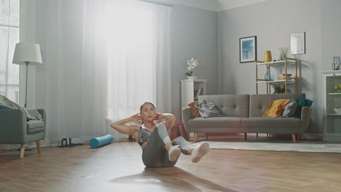 Montage with Fading Scenes of a Strong and Fit Beautiful Girl in a Grey Athletic Outfit Energetically Exercising in Her Bright and Spacious Living Room with Minimalistic Interior.