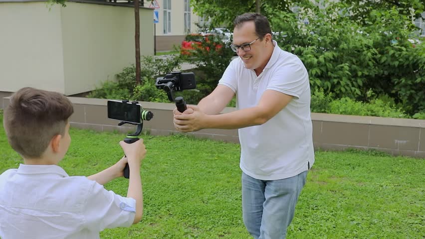 Father and son shoot each other by smart phones on hand cranes. Slow motion