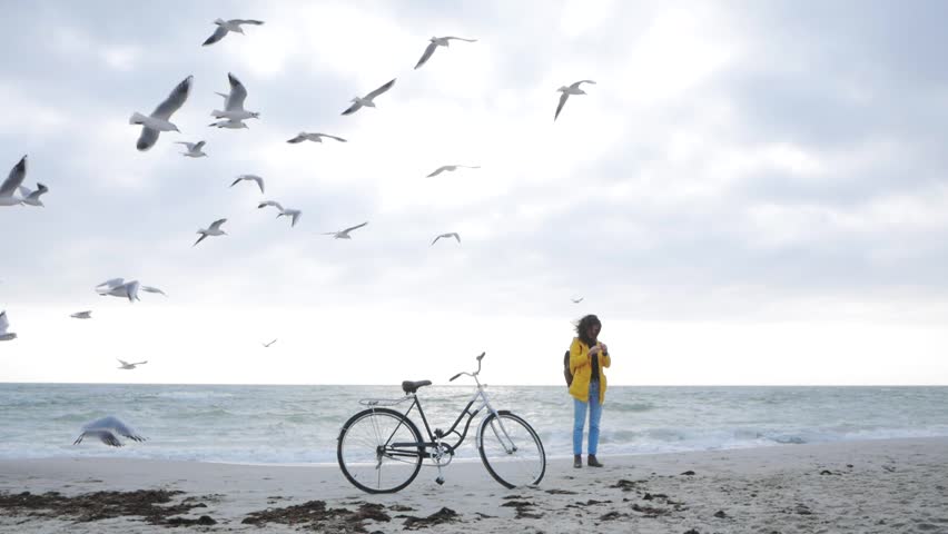 Young stilysh hipster female posing on the autumn or winter beach with retro bicycle 