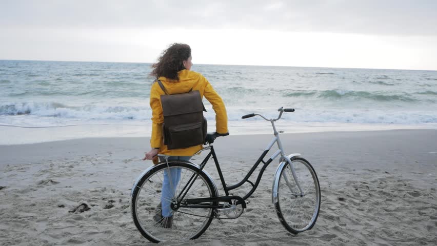 Young stilysh hipster female posing on the autumn or winter beach with retro bicycle 