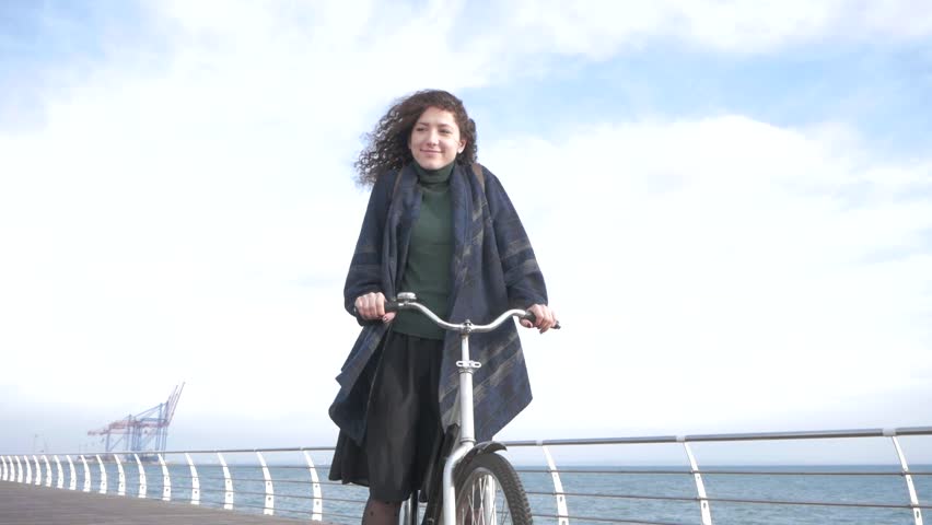 Young stilysh hipster female posing on the autumn or winter beach with retro bicycle 