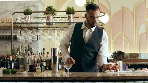 Young skillfull bartender preparing a classic Daiquiri cocktail in a beautiful modern trendy bar. Medium close shot on a RED camera.