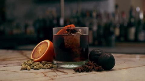 Fancy cocktail with orange and star anise on a marble countertop, in a beautiful bar.
Close shot on a RED camera.