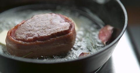 Bacon-wrapped beef tournedos, cooked in butter, garlic and thyme, in frying pan. Close up shot in 4K slow motion with Phantom Flex camera. Chef's Table, Food Network and cooking show inspired footage.