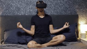 Man wearing VR Headset at bedroom. Doing yoga with glasses of virtual reality, meditates. Virtual reality concept. Moving camera