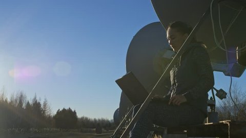 Woman student operator of institute of Solar Terrestrial Physics monitors communication equipment in notebook. Unique array solar radio telescope. Sun Solar Radio Telescope. The 'Quasar' observatory