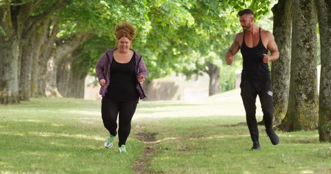 4K Exhausted obese woman working out with muscular fitness coach in the park