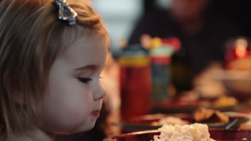 Toddler eating a holiday dinner with family. Caucasian family having a holiday meal together.