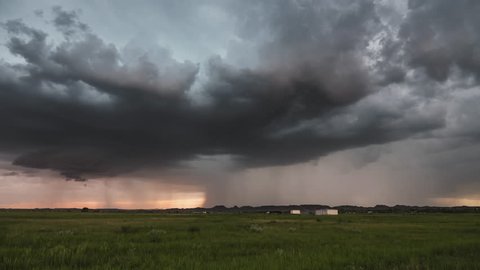 Time lapse of rain storm moving across the land as lighting strikes over the grassy plains.