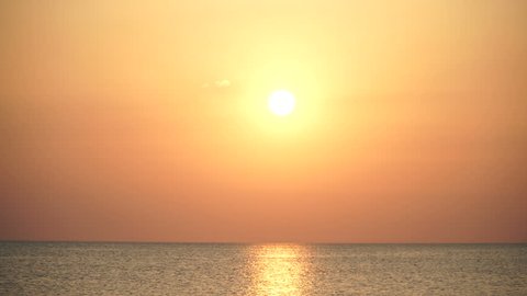 Unimaginably beautiful orange sunset. Dawn on the sea coast. The reflection of the sun in the ocean. The end of a hot summer day. Lovely background. 4K UHD. The sun is slowly approaching the horizon.