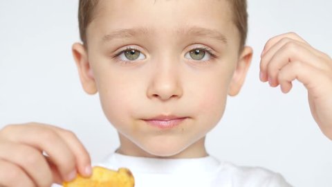 A child with pleasure and joy eating potato chips, on a white background, close-up.