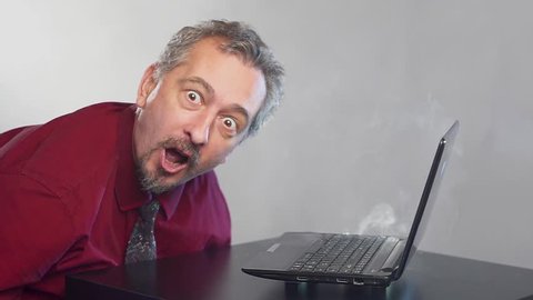 Crazy fanatical businessman working on a burning computer and dies.
