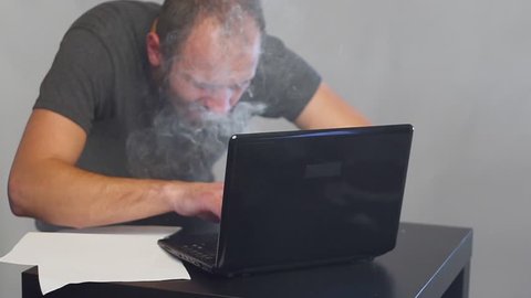 Crazy fanatical businessman working on a burning computer. Accountant report. Cryptocurrencies.