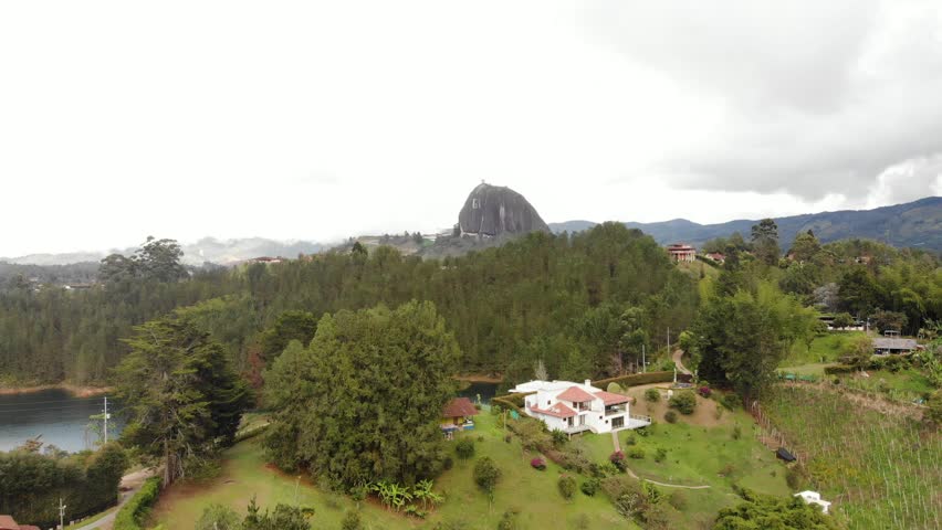Aerial Drone Shot Approaching La Piedra del Penol With View of Pine Trees and Country Houses. Guatape, Medellin, Colombia.