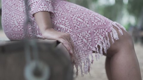 Close up shot on Female hand on wooden swing, Slow Motion Young Lady On Bench Puts Hand next to her pink Dress. Thinking joyful person enjoy time in nature