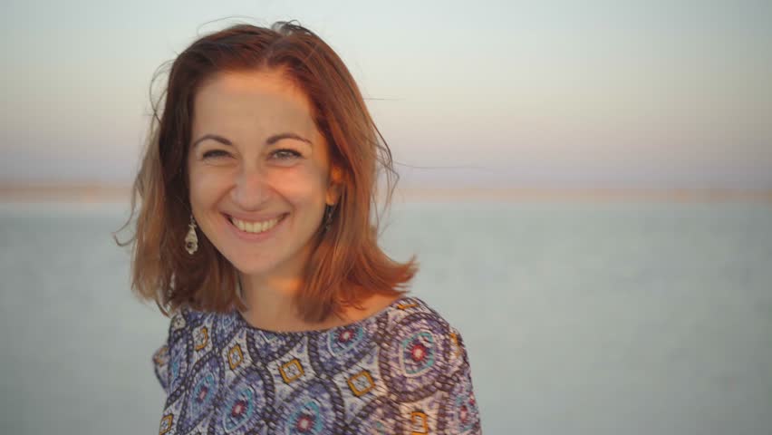 happy smiling girl enjoying the sunset sun, spinning around you, and closed her eyes to pleasure on the expanse of the Bascunchak salt lake at sunset during summer holidays