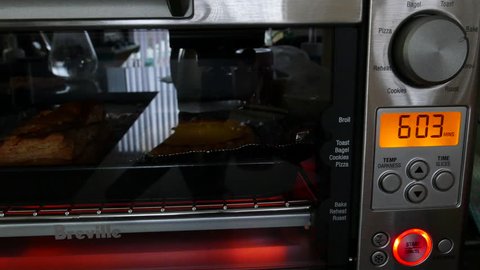 Coquitlam, BC, Canada - November 03, 2018 : Motion of egg tart baking and time counting down inside toaster oven at kitchen with 4k resolution