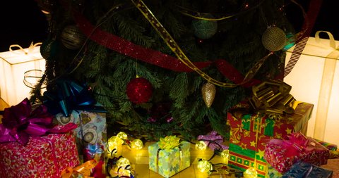 Christmas Gifts for the whole Family. The camera slowly goes down under the decorated Christmas tree under which there are gifts in colorful boxes