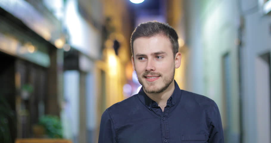 Front view of a happy couple or friends walking meeting and joking in the night in the street