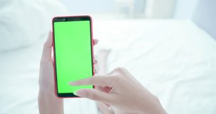 woman take cell phone with green screen in the bed at home