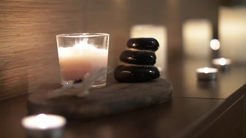 Cairn balancing stones with burning candles in the background. Home decoration. Pyramid of stones. Comfort in home. Stay at home in warmth and comfort