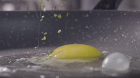 Falling of the egg and pieces of greenery into the frying pan. Slow motion