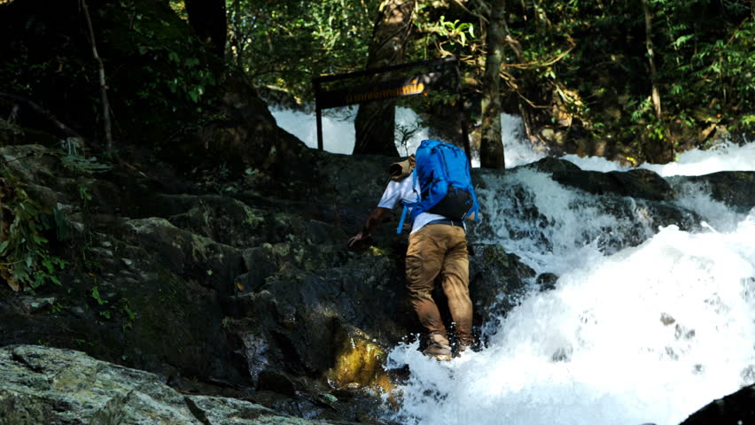 Man Traveler walking on waterfall at mountain in forest. Travel Lifestyle adventure vacations concept 