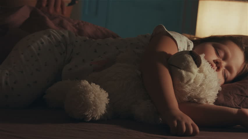 Sleeping baby happy and carefree in bed hugging a teddy bear toy. Mother cover with a blanket her child. Happiness in sleep, children without coughing. Royalty-Free Stock Footage #1019298025