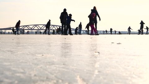ZWOLLE, THE NETHERLANDS - MARCH 2: People ice skating on a frozen lake next to the river IJssel in Holland during a beautiful winter day winter. People are enjoying this typical Dutch winter activity.