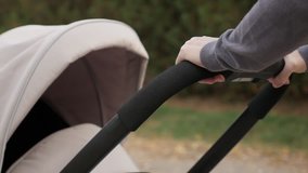 Mother holds stroller handle while walking slow motion footage