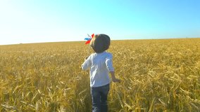 little boy running with toy wind turbine in hand at summer sunset nature outdoors Wheat field Happy kid child playing having fun pinwheel Happiness vacation childhood children happy family holiday