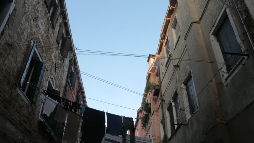 Traditional Venice street with clothes hanging out to dry between old houses, low angle, Italy.