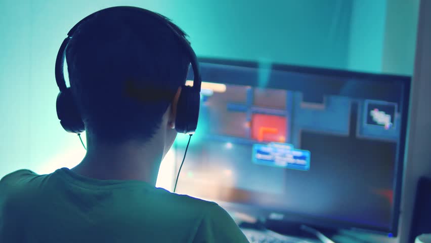 teen boy plays online game on computer via internet monitor in headphones. teenager man plays a video game at night. lifestyle teen boy and computer concept Royalty-Free Stock Footage #1019310454