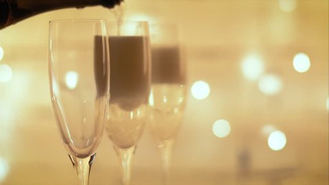 pouring champagne from bottle into a flutes over flashing light background