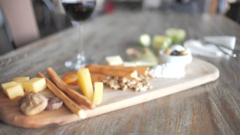 close-up cheese plate and snacks next to a glass of red wine