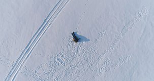 Woman is laying on tubing in the snow. Camera slowly rising. Aerial footage, high view.