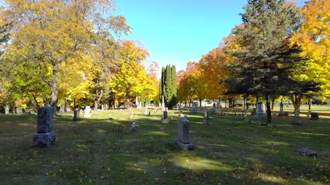 Drifting slowly thought Autumn cemetery with colorful trees, leaves.
