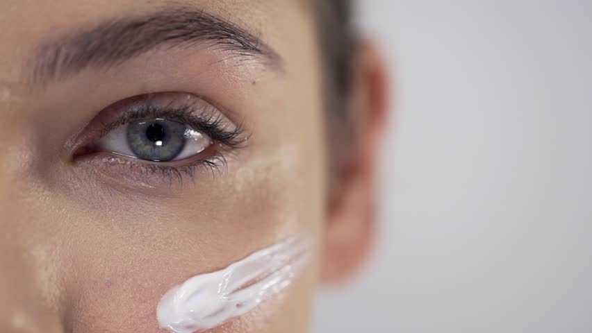 Young pretty woman applies face cream on her cheekbones, applying cream in circular motions, skin care, natural cosmetics, face care | Shutterstock HD Video #1019332702