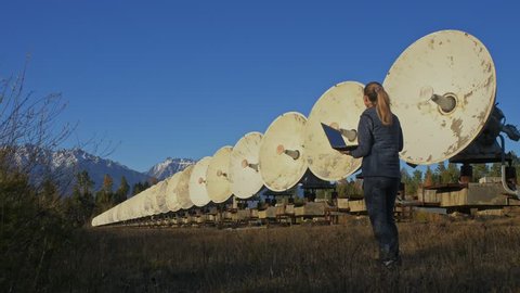 Woman student operator  monitors communication equipment in notebook. Unique array solar radio telescope. 