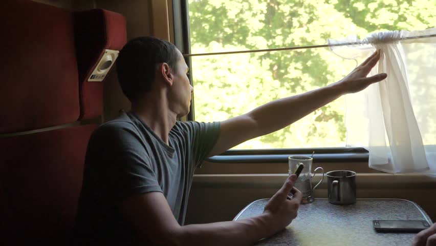 Profile portrait of young positive man traveler and smiling through the pictures via social media. slow motion video. uploading photo using cell lifestyle phone while riding home by train wagon