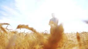 old farmer man baker holds a golden bread and loaf in ripe wheat field against the blue sky. slow motion video. successful agriculturist in field of wheat. harvest time. old man baker bread baking