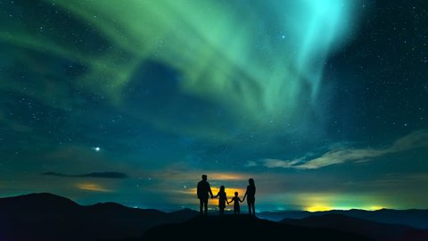 The family standing on the rock on the northern light background. time lapse