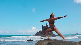 Calm girl is meditating in the mountains, bright sunshine on the background. In slow motion video. Yoga time in tenerife