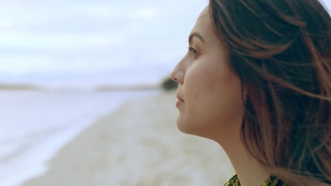 Young woman looking out at the water on a beach in Australia with soft day lighting. Close up shot on 4k RED camera