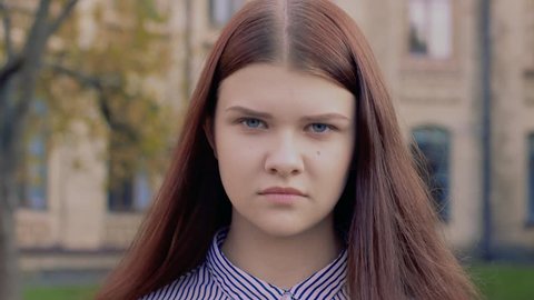 Emotional video-portrait nodding not approvingly beautiful young girl. Blue-eyed brown-haired lady angrily disagrees and looks into the frame