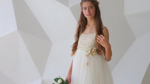 Young teen girl in a beautiful dress posing with flowers on a white background. Celebrate daughter’s coming-of-age. First moon party concept. 