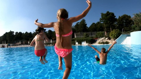 Three kids jumping in the pool, filmed in slow motion