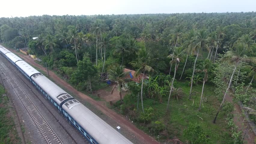 A aerial shot of passenger journey train rides in jungle Indian Railways, Indian trains, all-coach train; way local commuter tram. Aerial view of train passing Kerala Southern India. Royalty-Free Stock Footage #1019391673