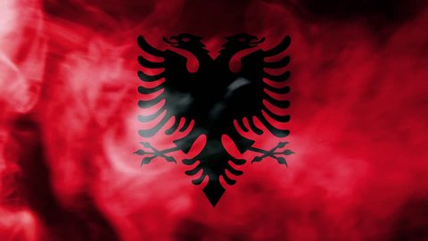National flag of Albania made from colored smoke isolated on black background. Abstract silky wave background