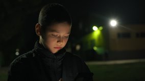little boy watching videos on the phone on the street at night, 4k